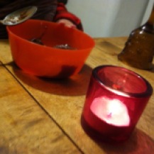 Rosane Kerze auf Holztisch vor Müslischale