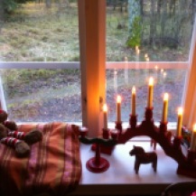 roter Schwippbogen im Schweden Fenster, Elch daneben auf einem Kissen, Holkerzenständer schwedisch bemalt und Dalahästlein